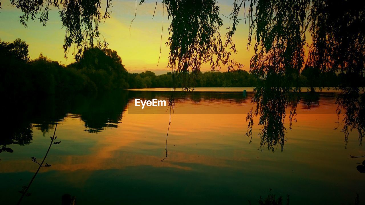 SCENIC VIEW OF CALM LAKE AT SUNSET