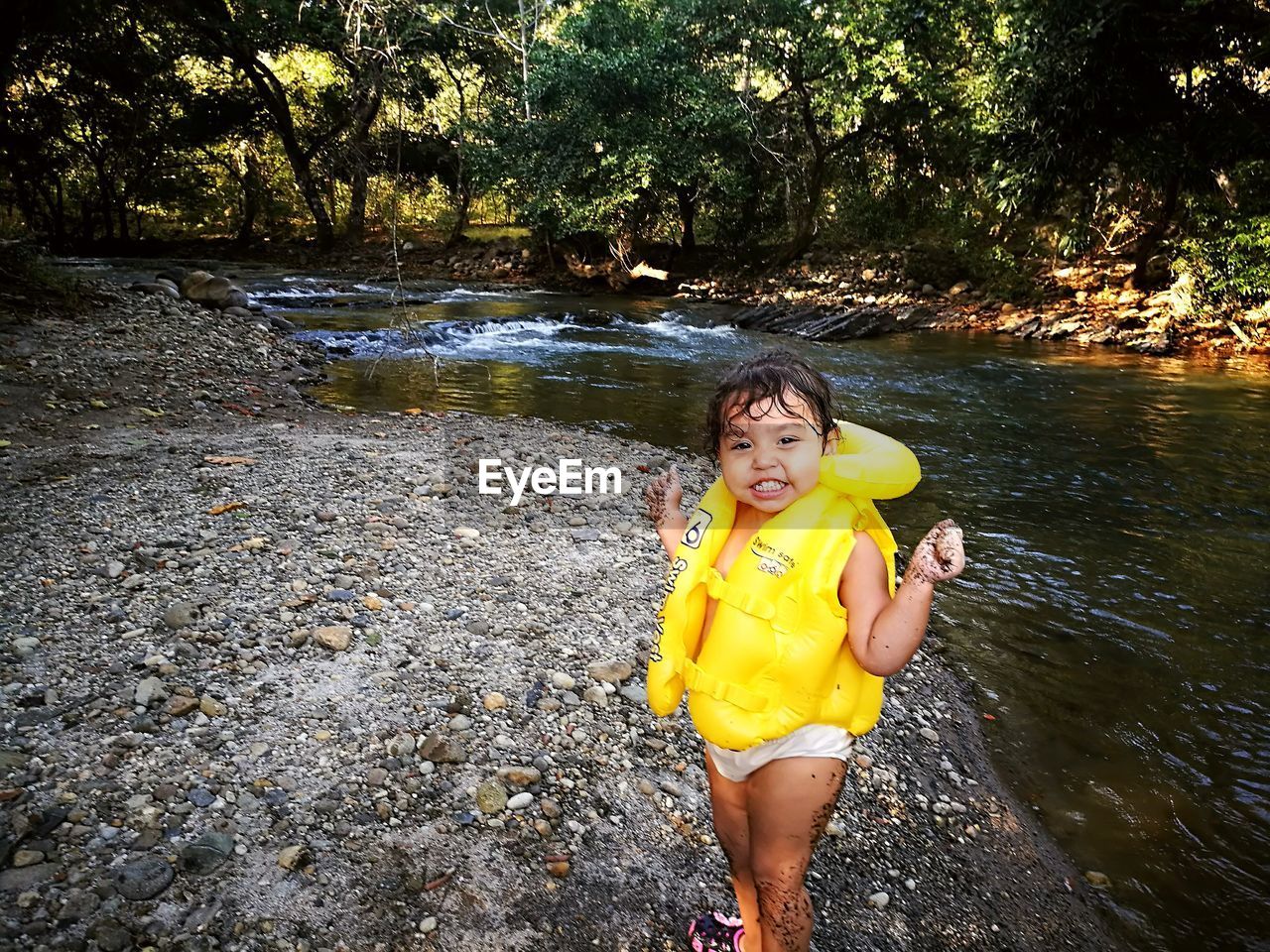 PORTRAIT OF HAPPY GIRL IN SWIMMING POOL AGAINST TREES