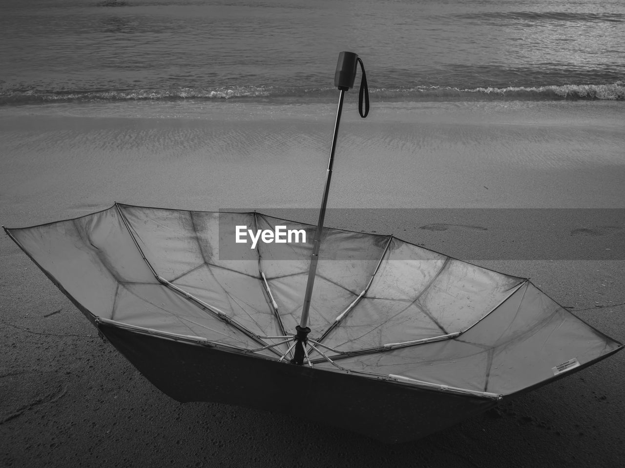 HIGH ANGLE VIEW OF UMBRELLA ON SHORE