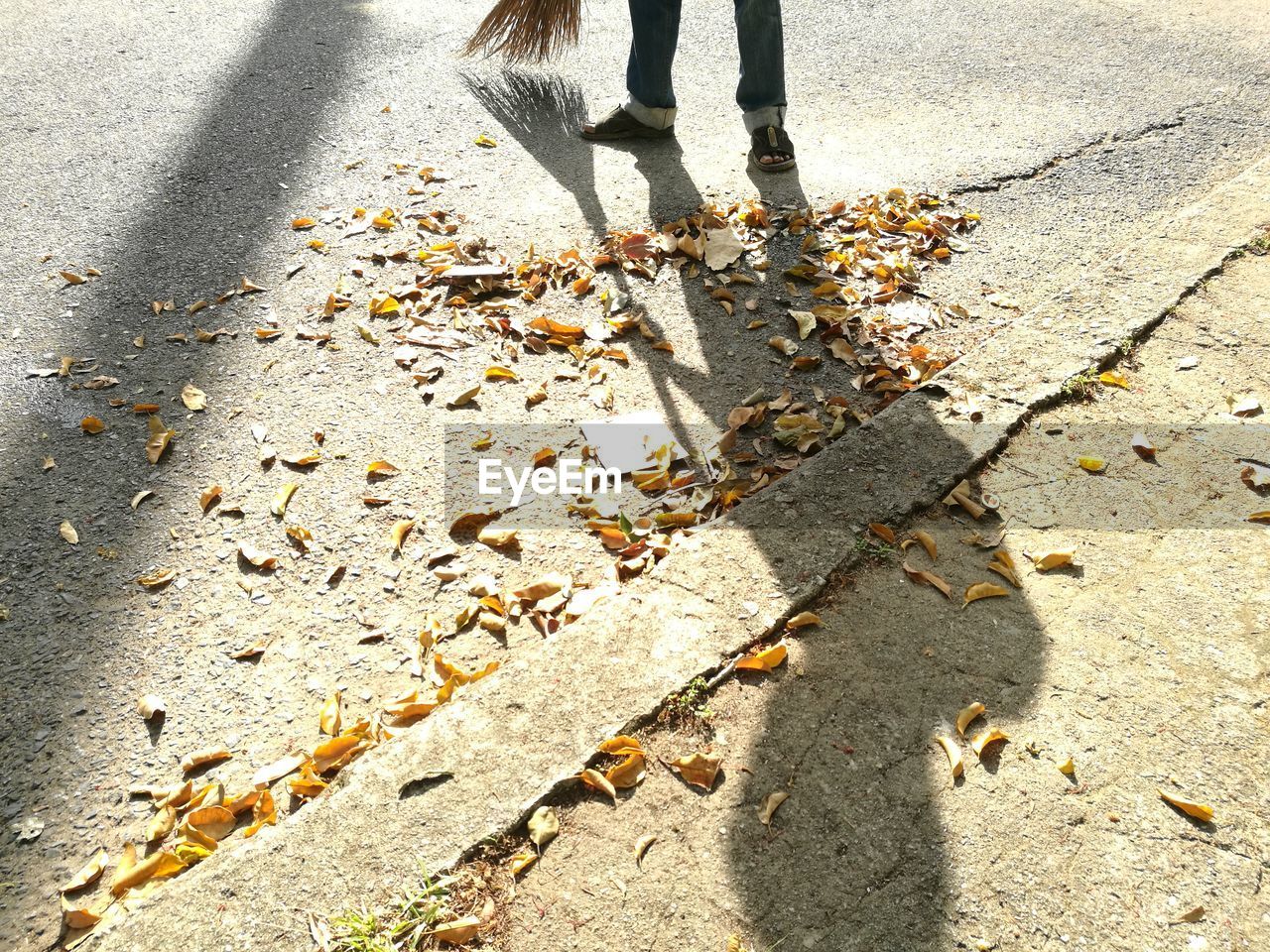 LOW SECTION OF MAN WITH SHADOW ON ROAD