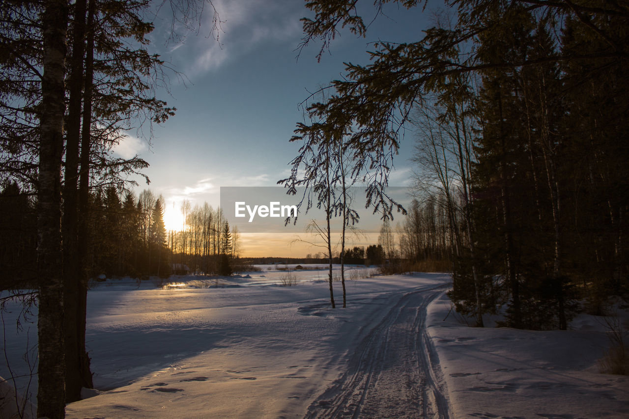 SNOW COVERED LAND AGAINST SKY AT SUNSET