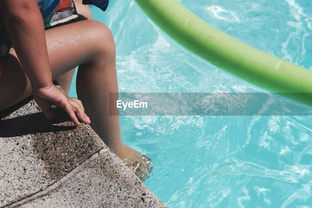 Low section of woman relaxing at poolside