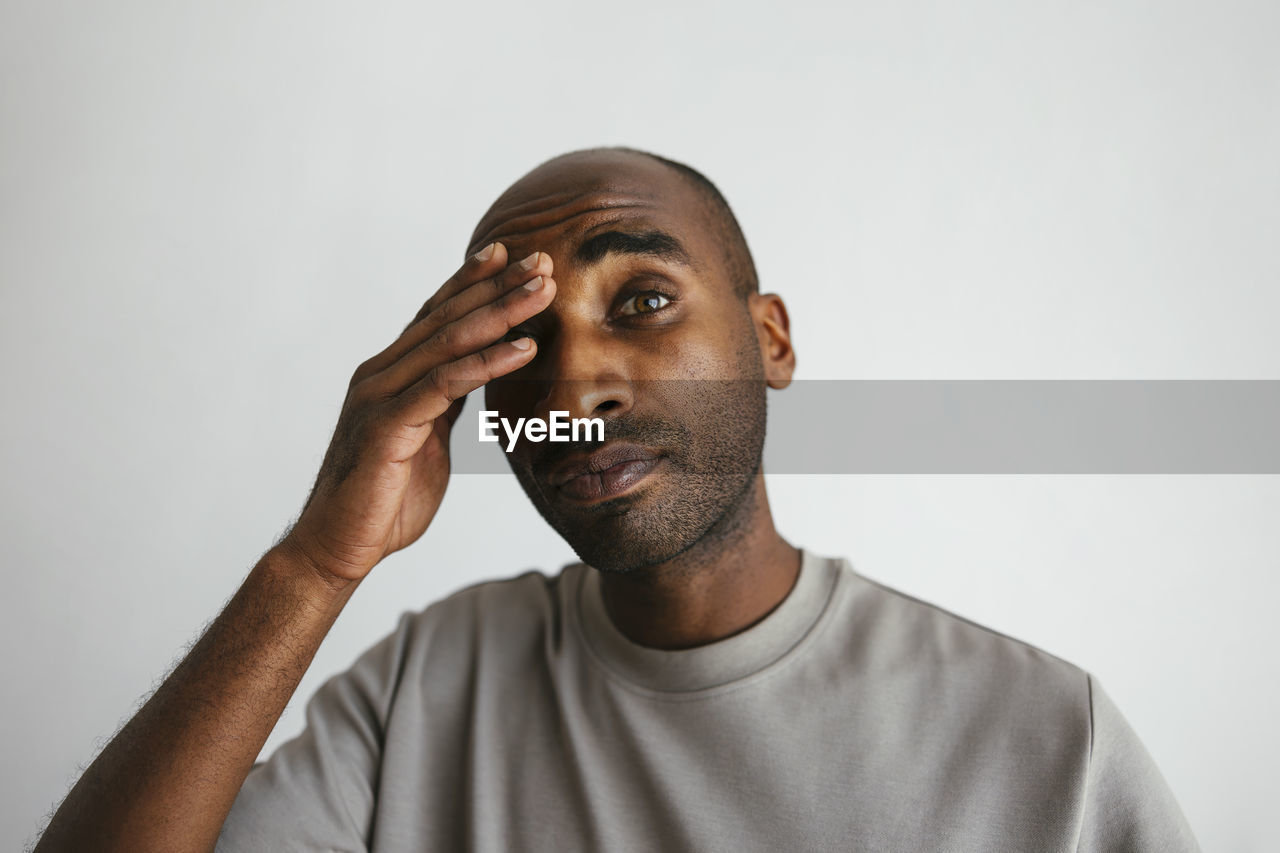 Man with head in hand against white background