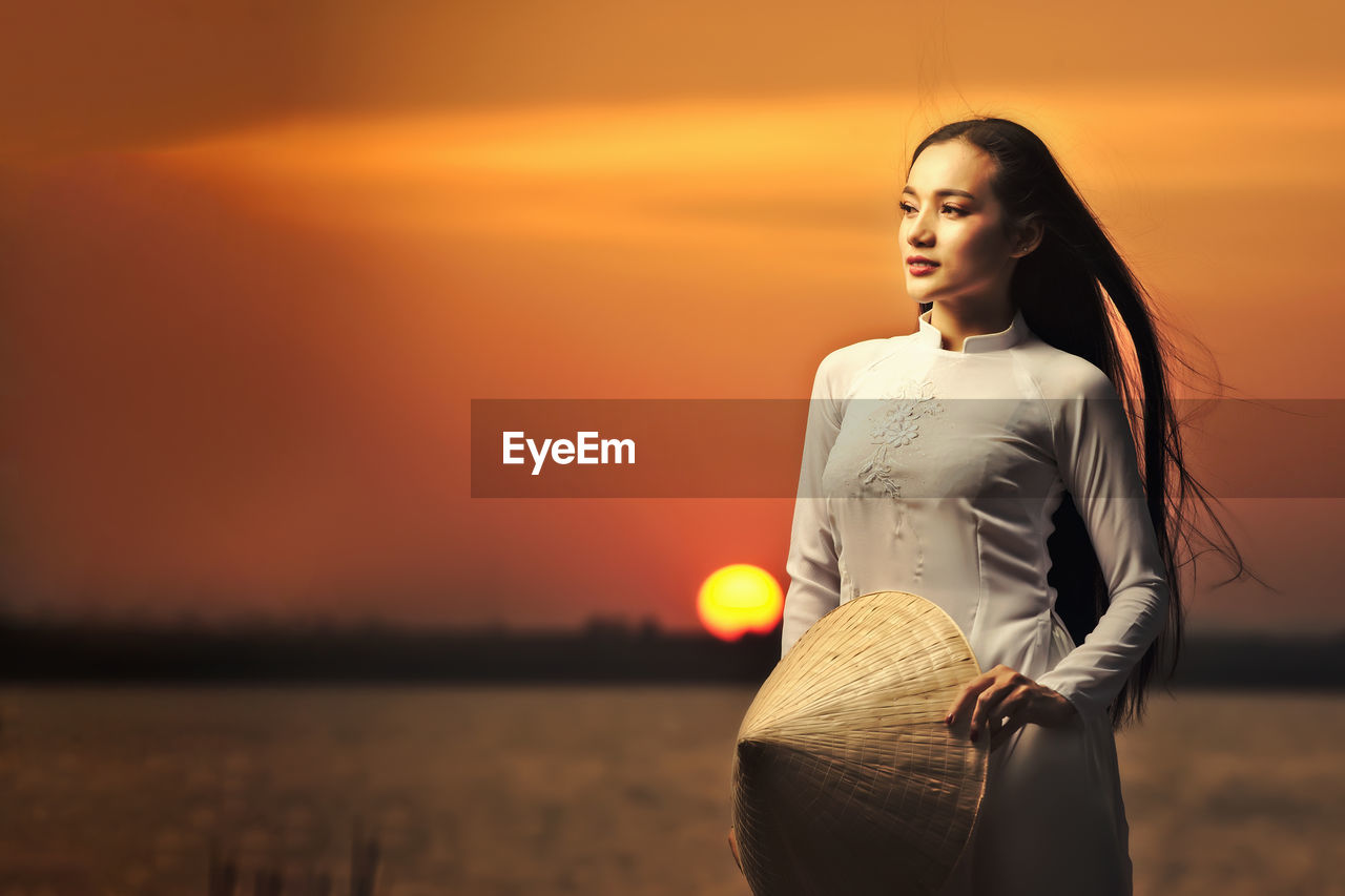 Portrait of beautiful asian girls with ao dai vietnam traditional dress on sunset landscapes.