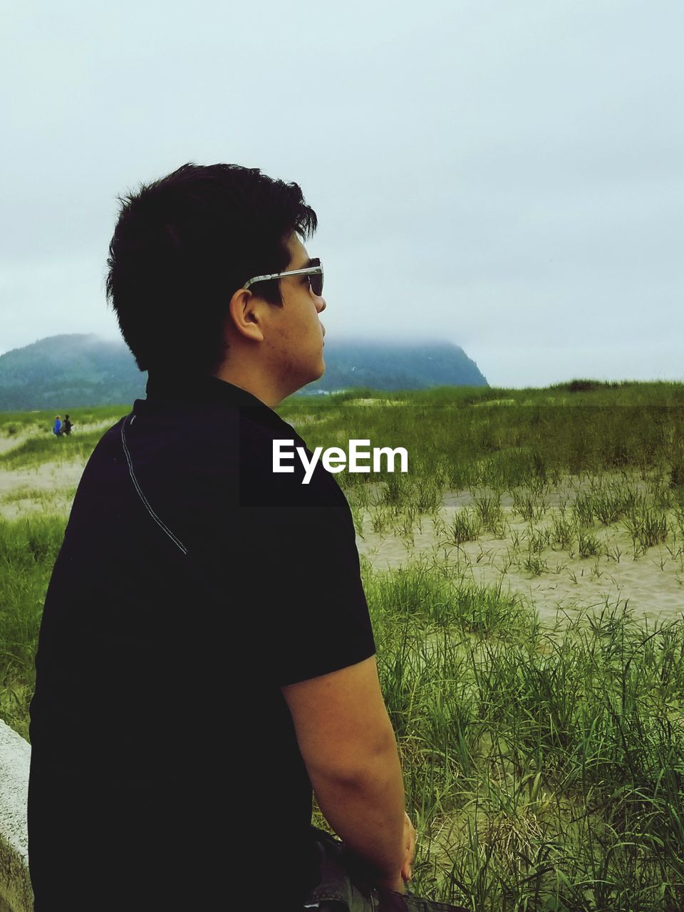 SIDE VIEW OF YOUNG WOMAN WEARING SUNGLASSES STANDING ON FIELD