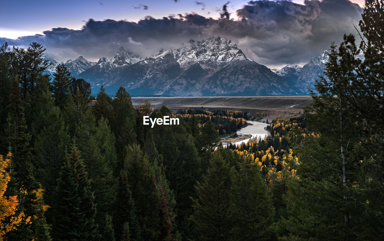 View of trees and mountains against cloudy sky