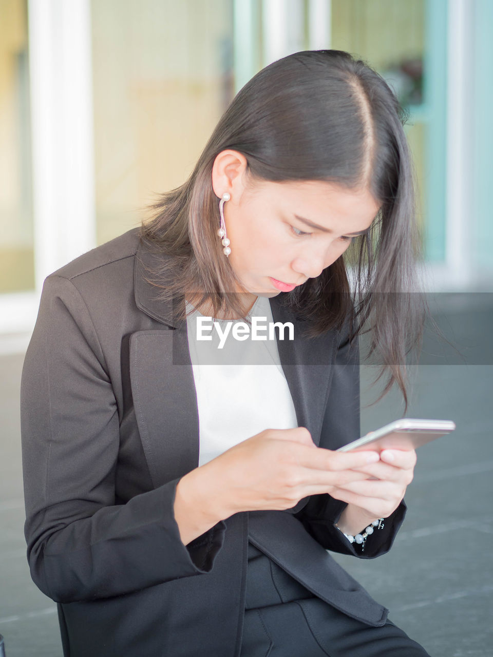 Businesswoman using smart phone while sitting outdoors