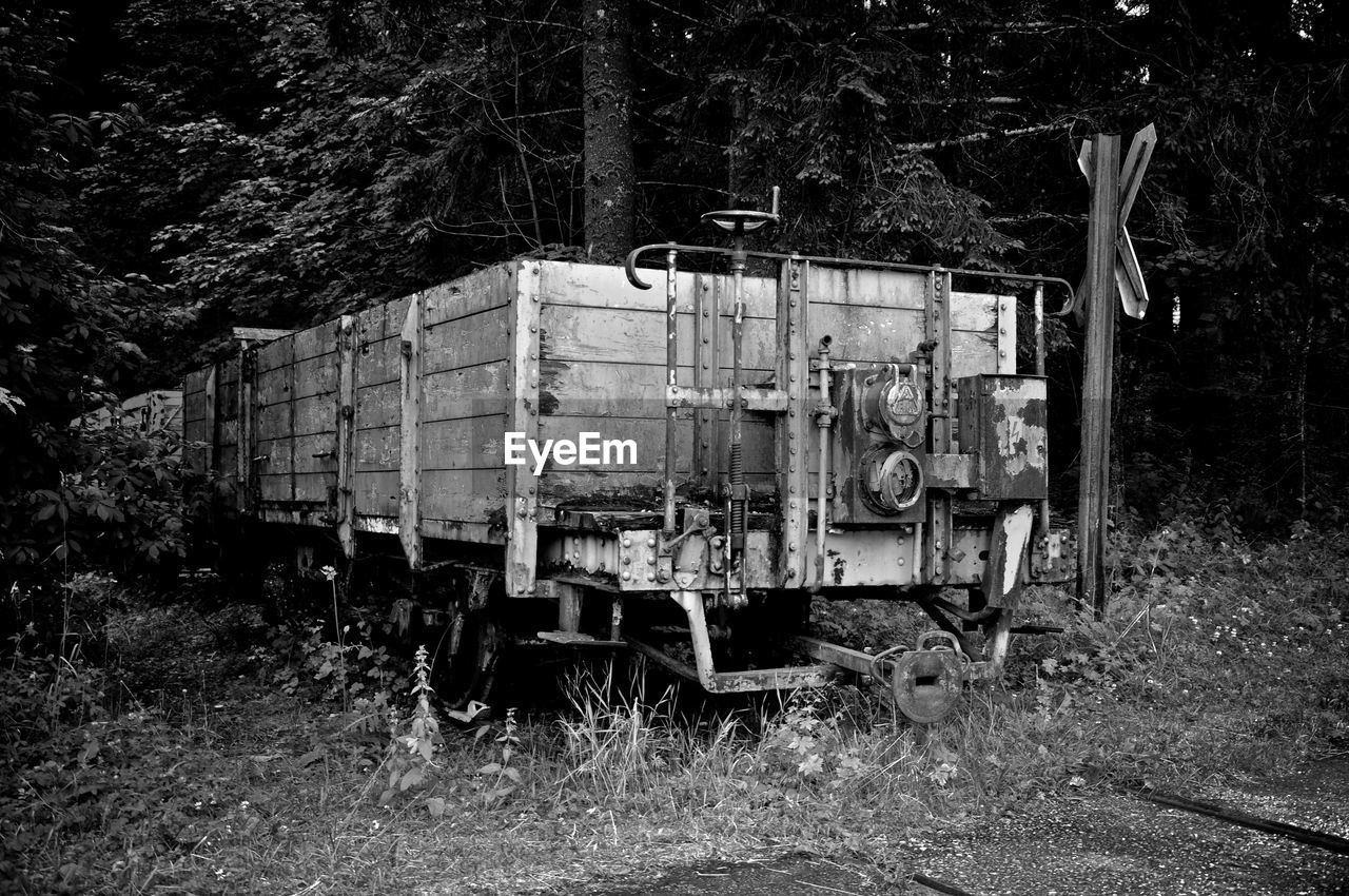 Abandoned train on field against trees