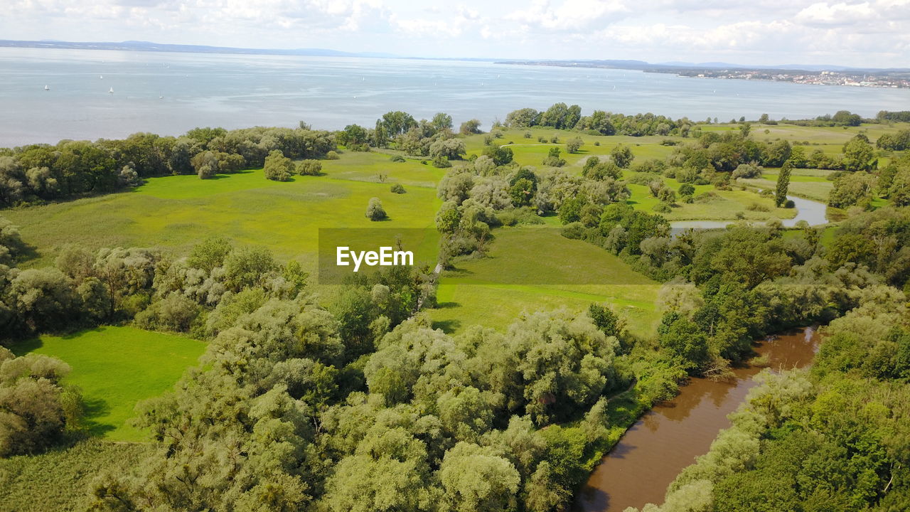 High angle view of agricultural field by sea against sky