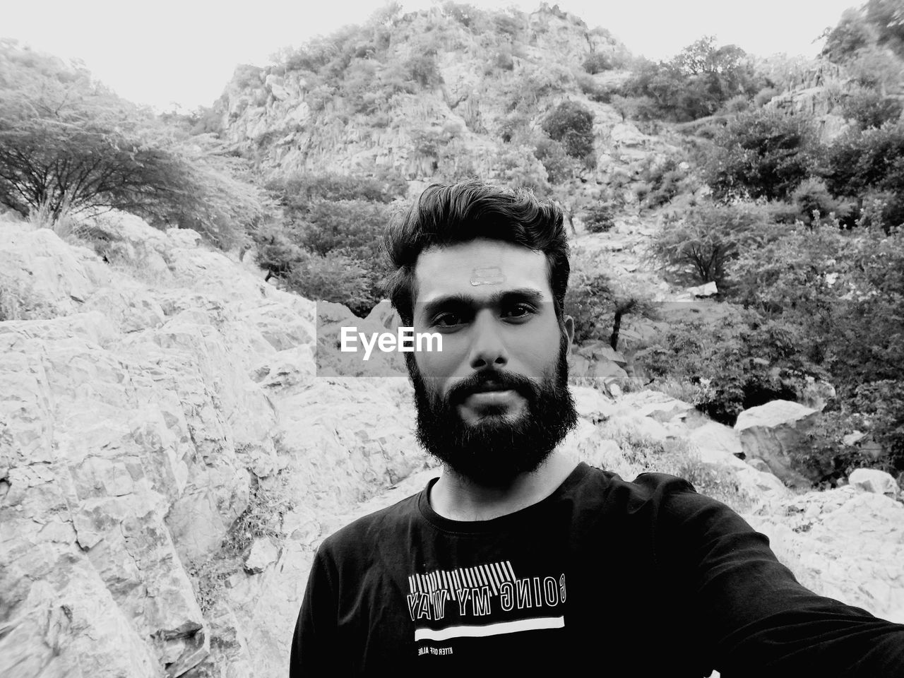portrait, one person, looking at camera, front view, black and white, young adult, leisure activity, men, monochrome photography, black, beard, monochrome, lifestyles, adult, day, casual clothing, facial hair, headshot, nature, white, mountain, standing, land, waist up, outdoors, person