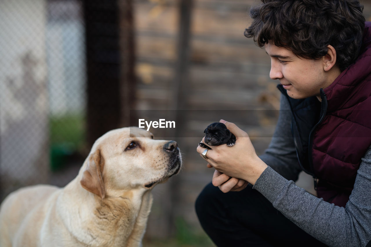 Side view of man with dog. young man holding a little puppy of labrador in his hands