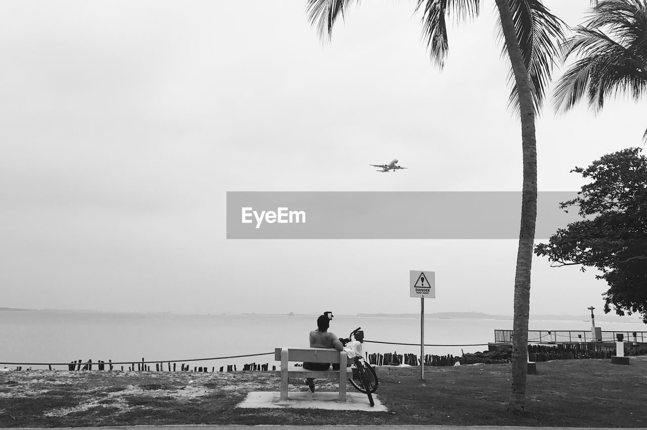 Man recording plane on beach