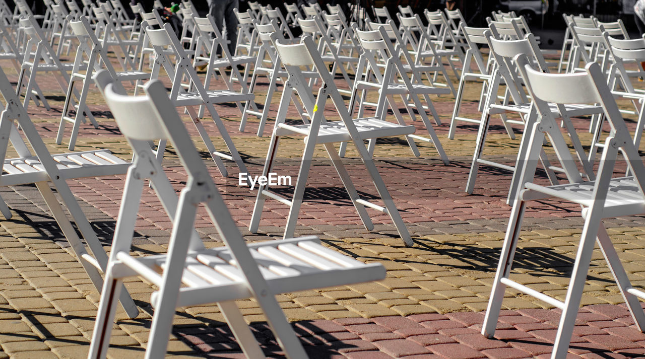 White folding chairs are placed on the square on pavement. quarantine restrictions, mass events