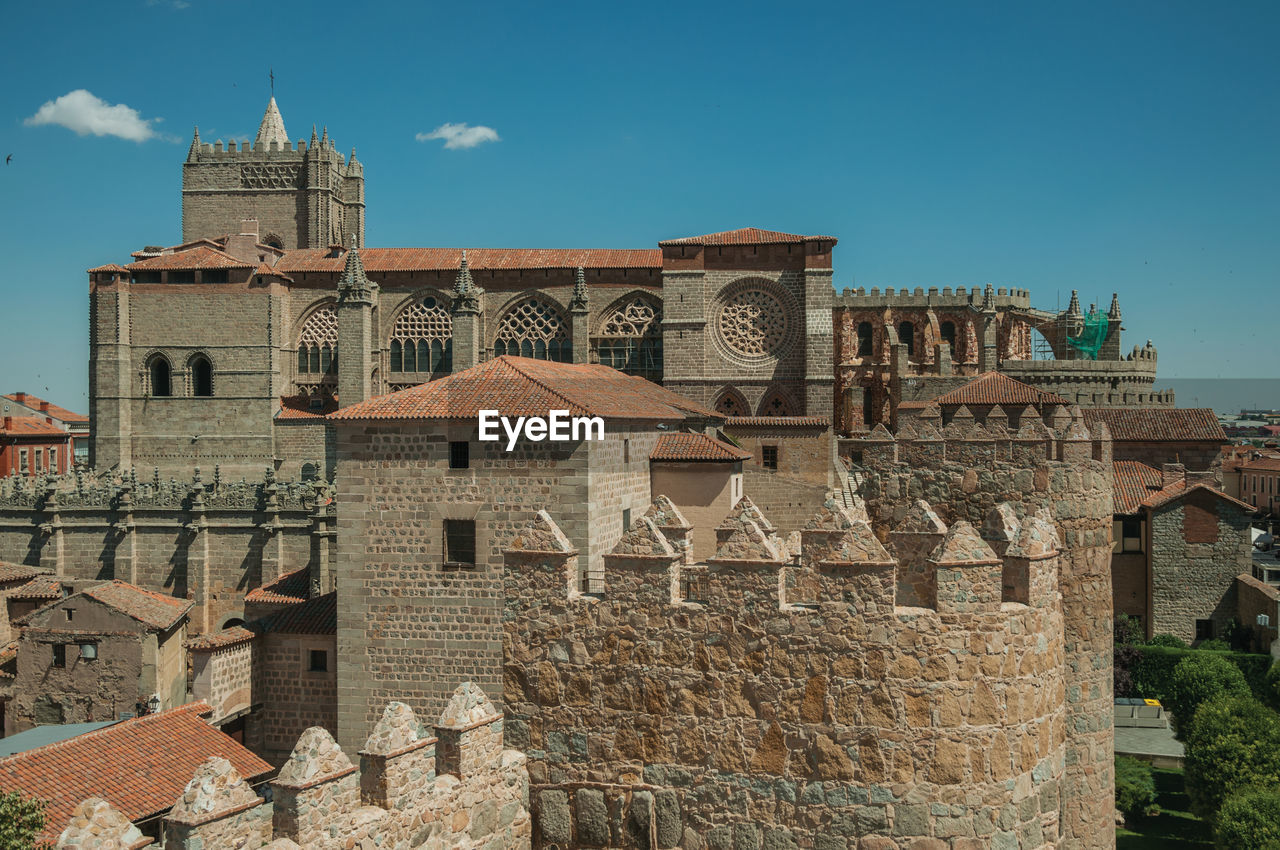 Pathway over stone wall with battlement around the town and side view of cathedral in avila, spain.