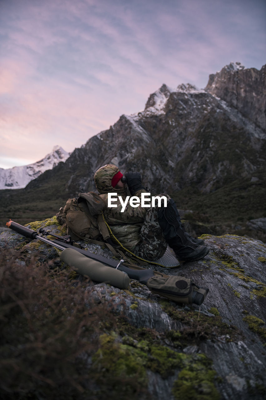 Hunter in mountains looking through binoculars