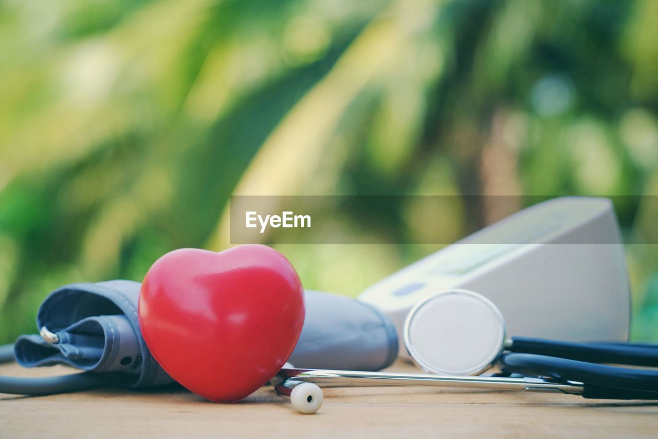 Close-up of stethoscope and heart shape on table