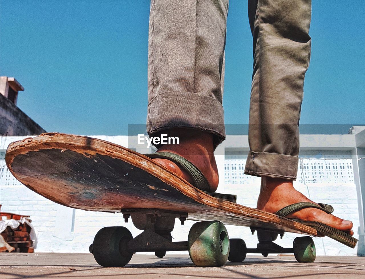 LOW SECTION OF MAN SKATEBOARDING ON SKATEBOARD AGAINST SKY