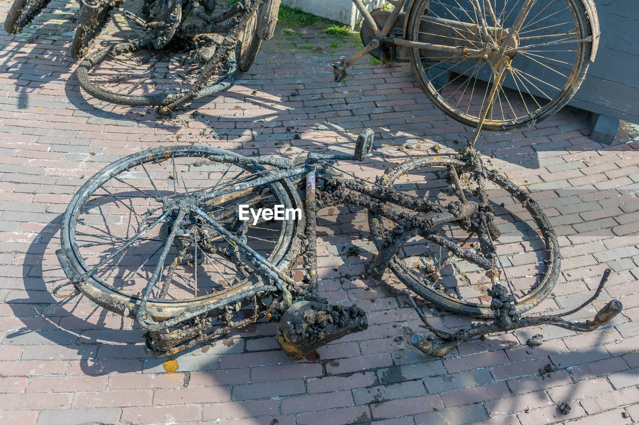 HIGH ANGLE VIEW OF BICYCLES PARKED ON FOOTPATH