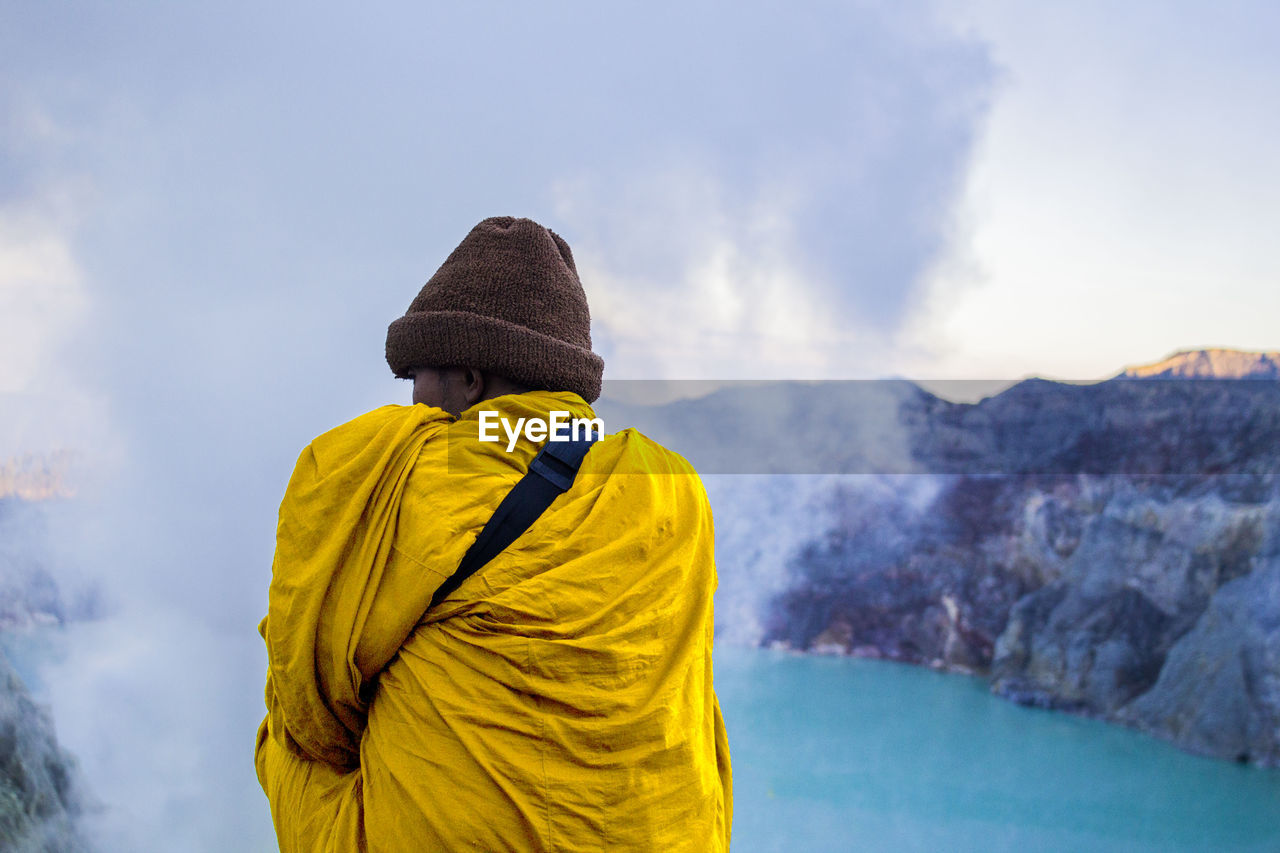 Rear view of man with scarf standing on mountain