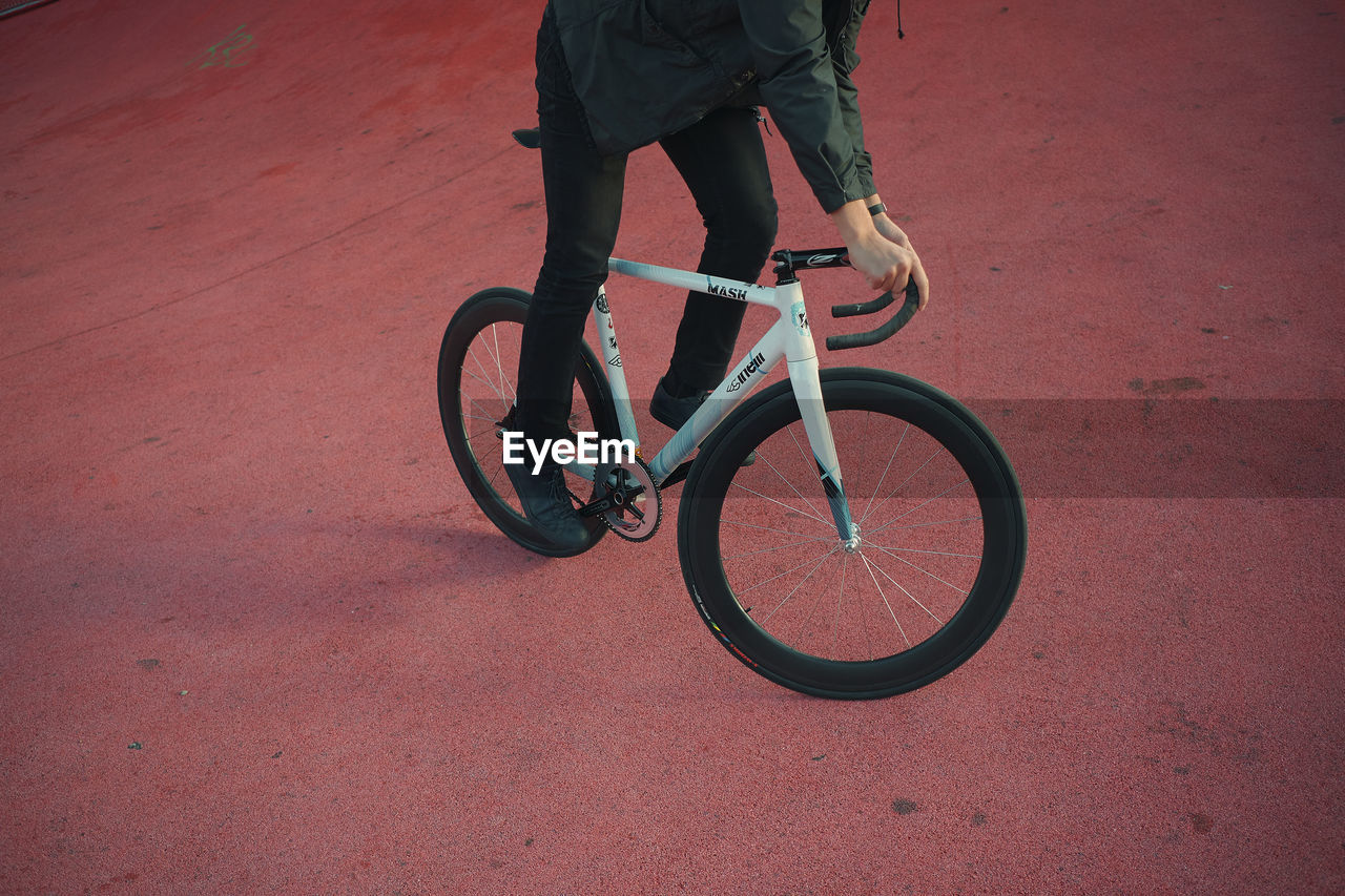 LOW SECTION OF MAN RIDING BICYCLE ON RED WALL