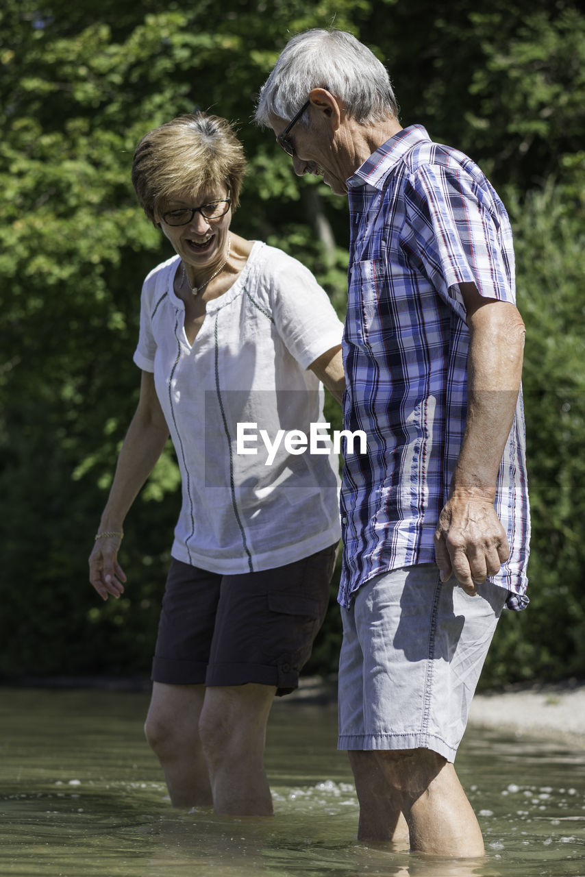Active senior couple walking in lake against trees