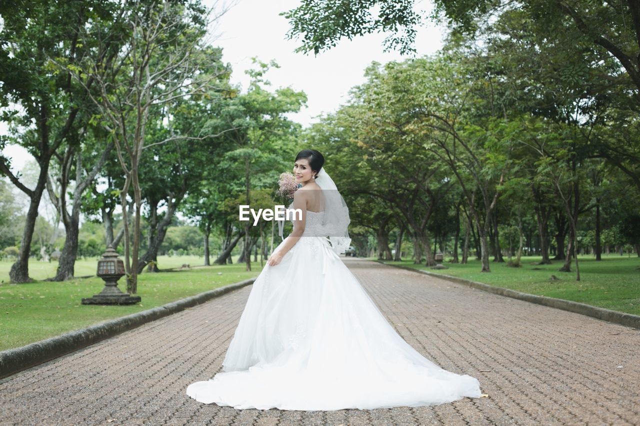 Portrait of bride standing on footpath at park