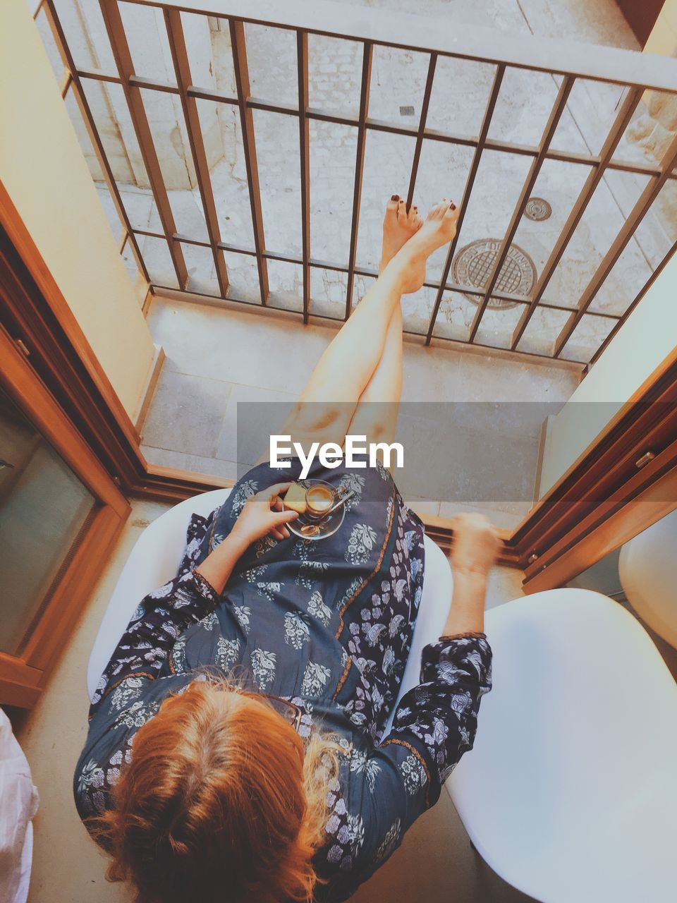 High angle view of woman relaxing by balcony at home