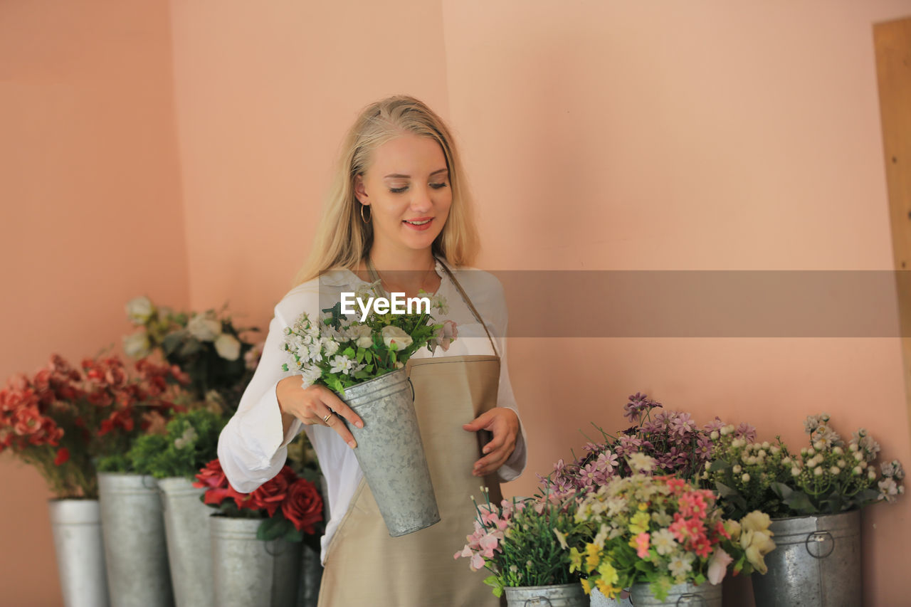 Beautiful blonde hair girl standing with in  retails flora shop. small business owner concept.