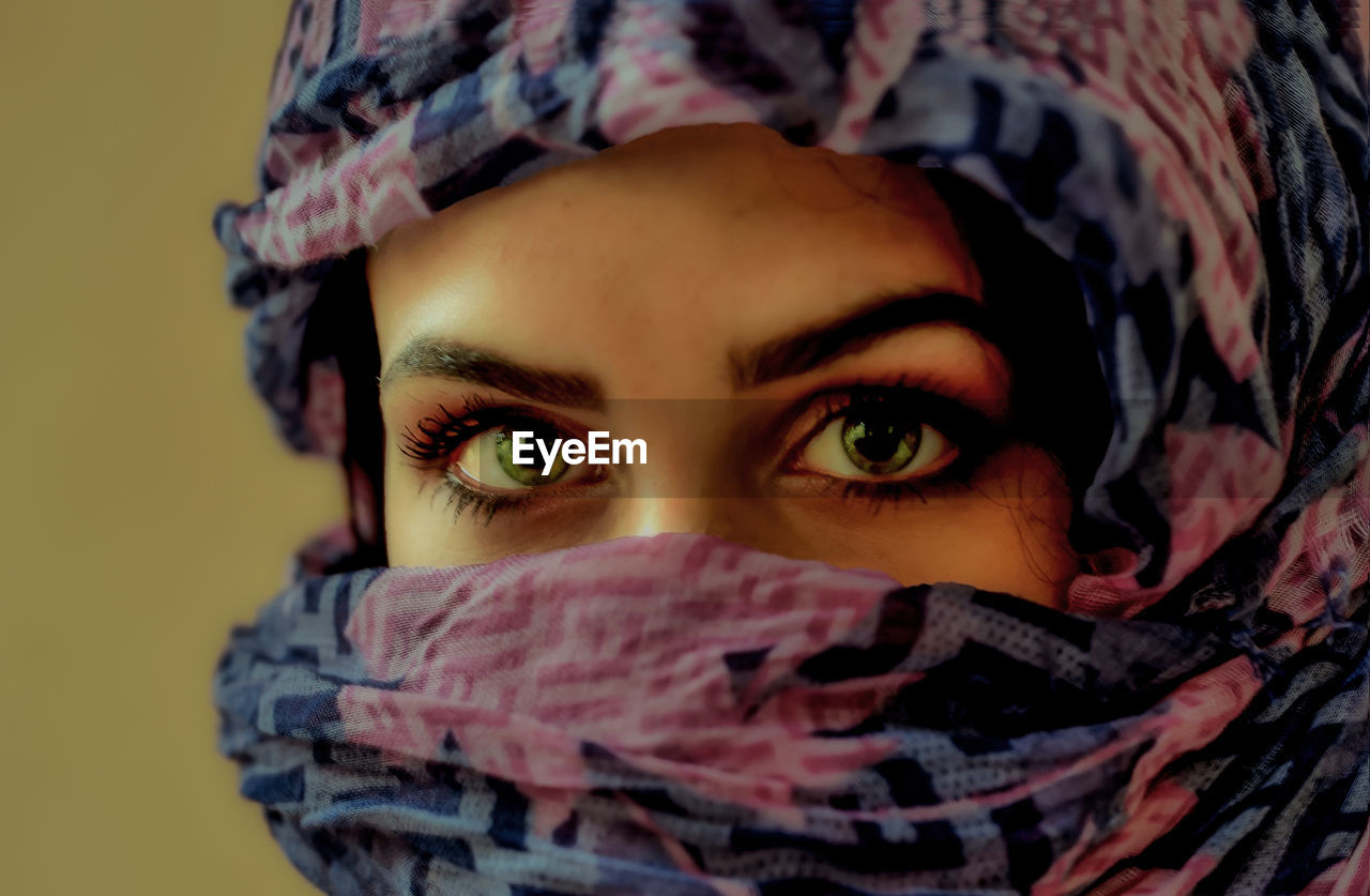 Close-up portrait of young woman covering face with scarf