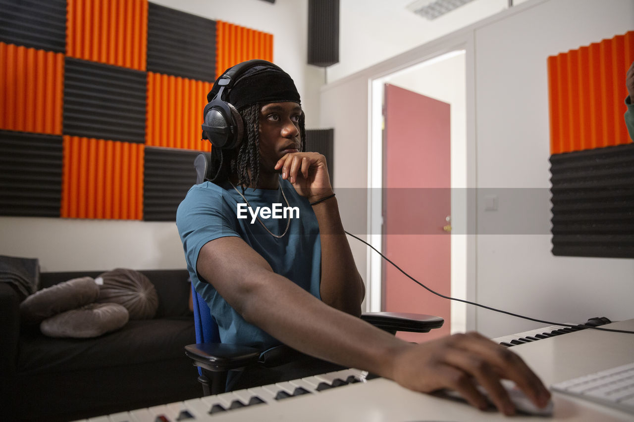 Sound engineer with hand on chin mixing song in recording studio