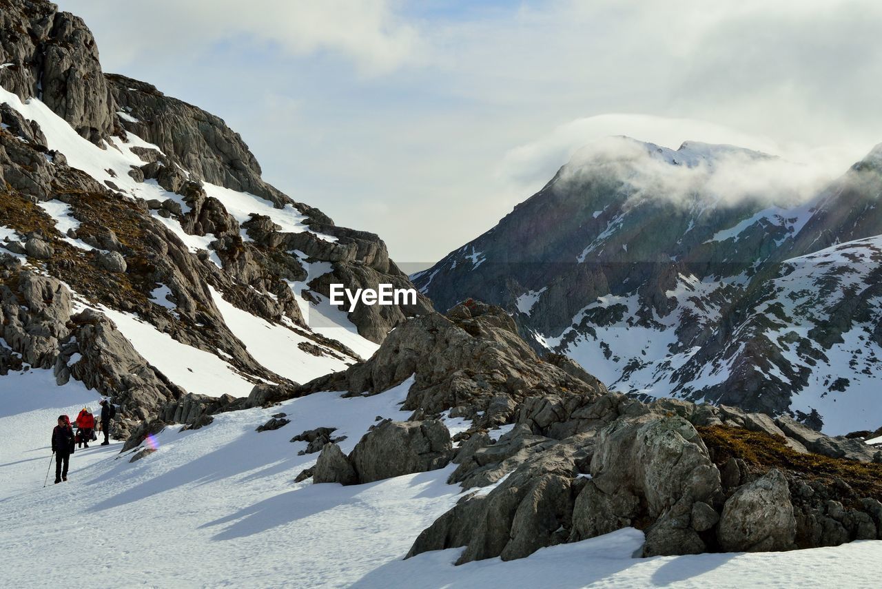 snow, mountain, winter, cold temperature, sports, adventure, mountain range, scenics - nature, environment, leisure activity, beauty in nature, activity, landscape, snowcapped mountain, sky, nature, winter sports, travel, cloud, hiking, travel destinations, one person, vacation, climbing, ski mountaineering, mountain climbing, holiday, adult, extreme sports, trip, day, full length, ski touring, ridge, mountaineering, motion, men, skiing, outdoors, backpack, lifestyles, recreation, exploration, walking, non-urban scene, mountain peak, tourism, land, arête, rock, extreme terrain, summit, sunlight
