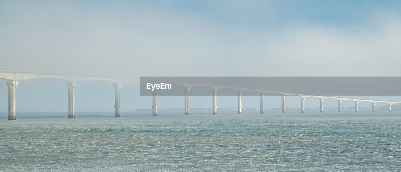 water, sky, bridge, built structure, sea, architecture, horizon, nature, no people, environment, day, wave, transportation, fog, copy space, scenics - nature, waterfront, outdoors, beauty in nature, beam bridge, tranquility, ocean, in a row, horizon over water, blue, tranquil scene, architectural column, cloud, travel, pier, environmental conservation, coast, beach