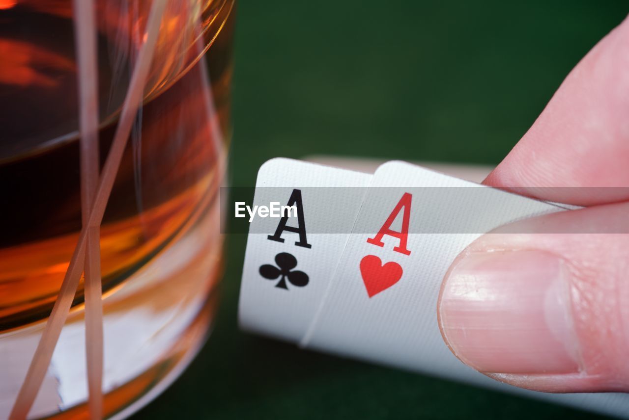 Cropped image of hand holding cards by drink on table