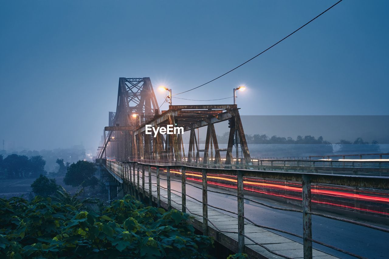 Light trails on bridge against sky