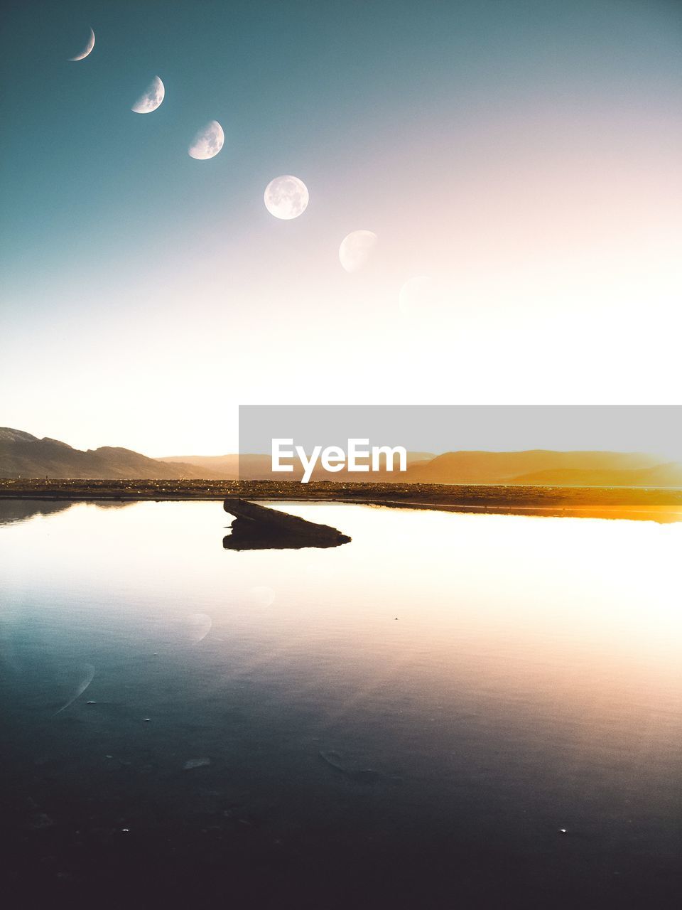 Scenic view of moon over lake at sunset