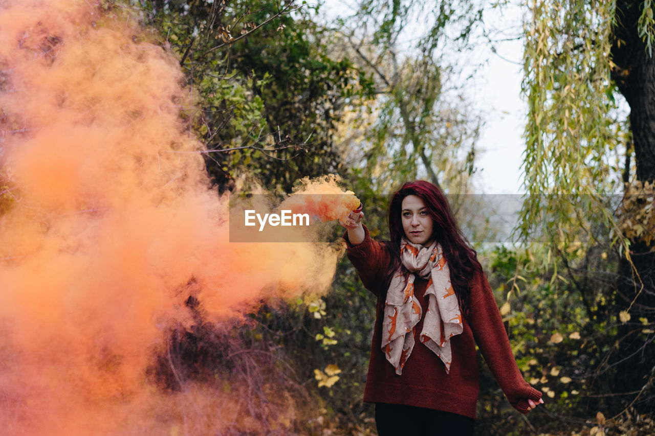 Woman with orange distress flare standing on field