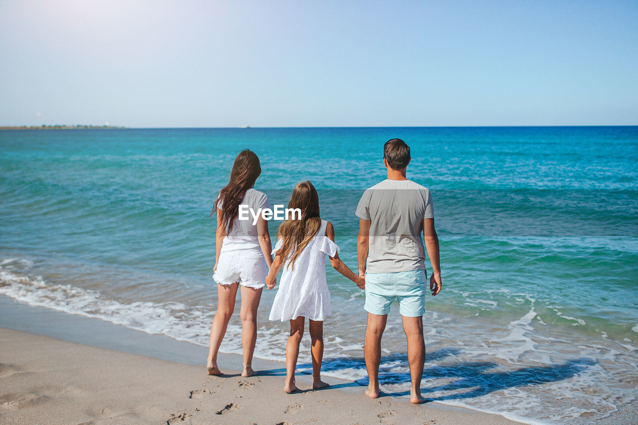 rear view of woman walking on beach against clear sky