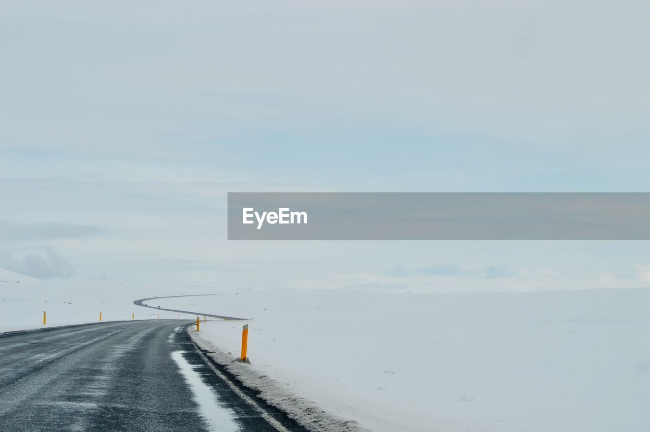 Road by sea against sky during winter