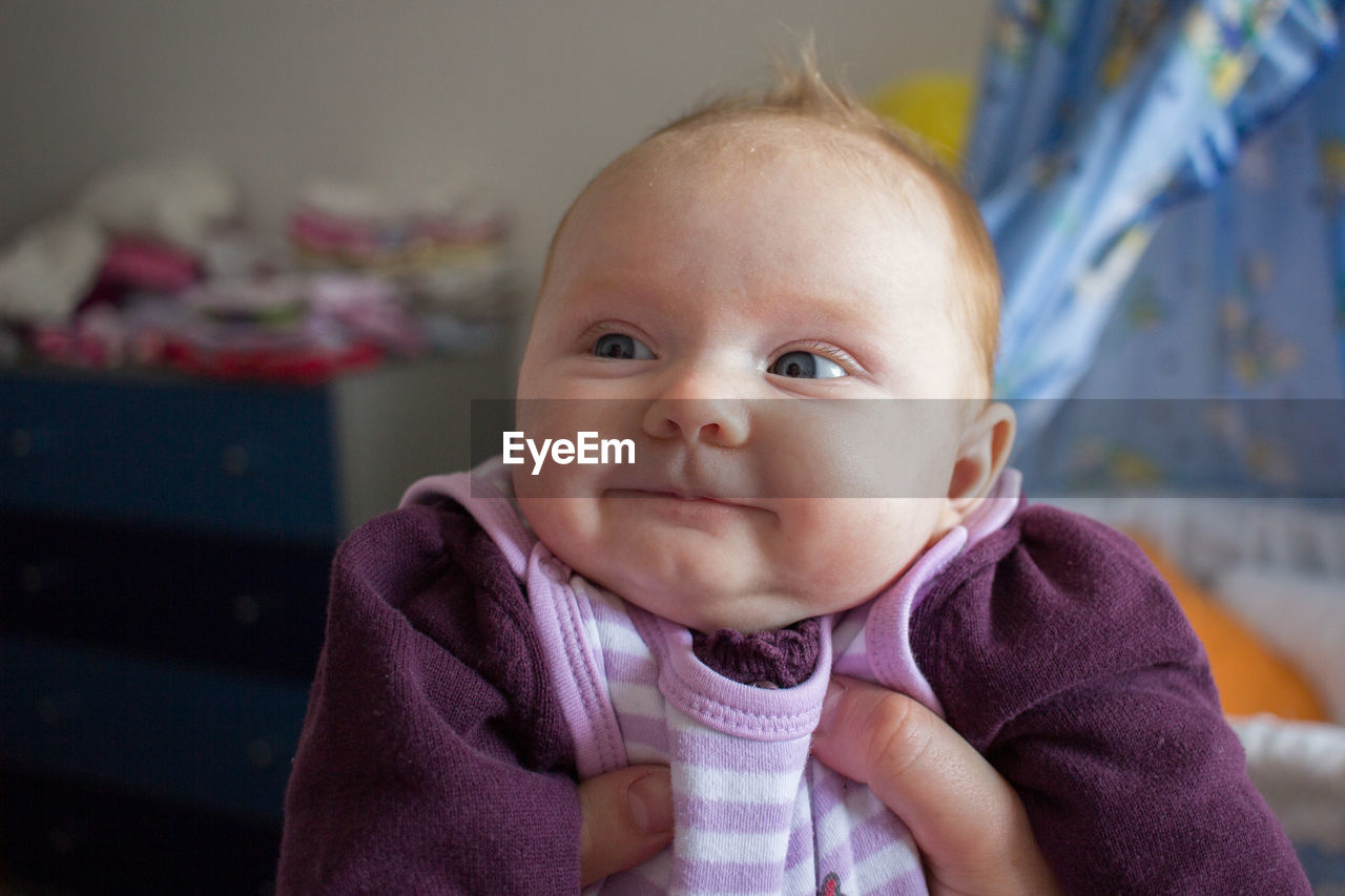 Close-up of cute baby girl looking away at home