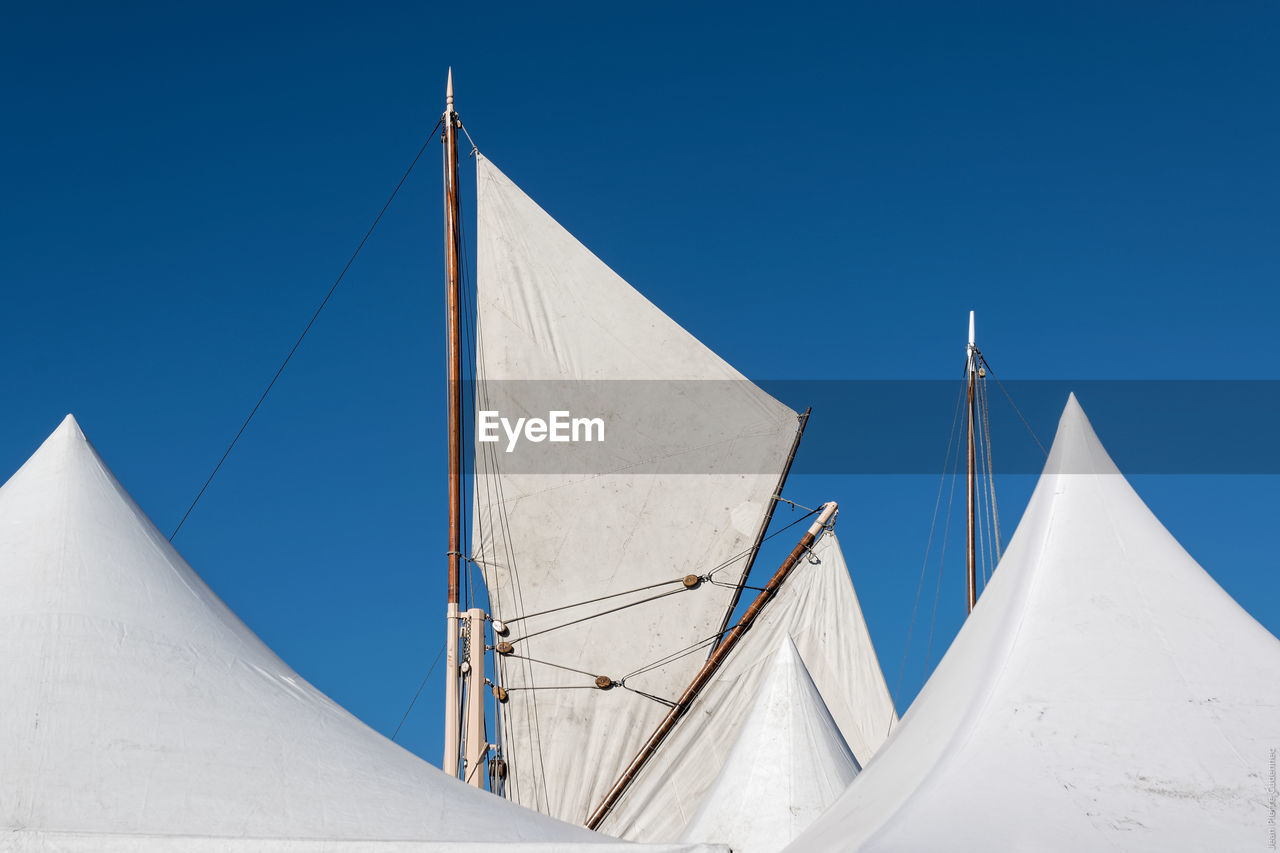 Low angle view of sailing ship masts against clear blue sky