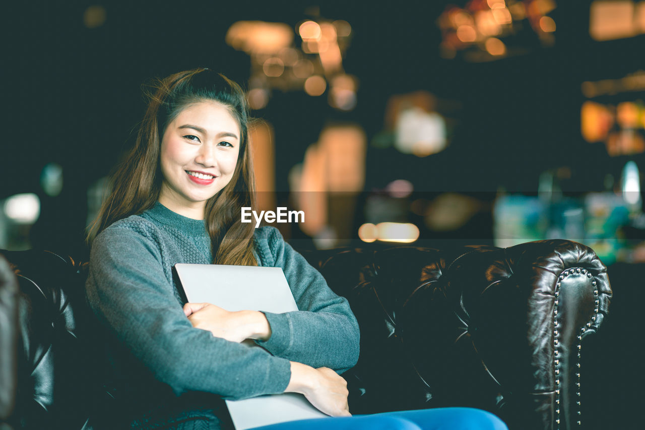 Portrait of smiling woman holding laptop