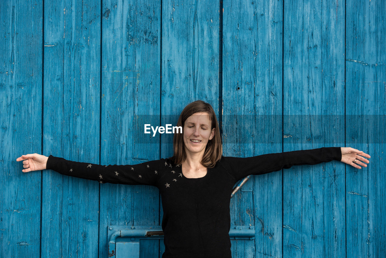 Smiling young woman standing against blue wall