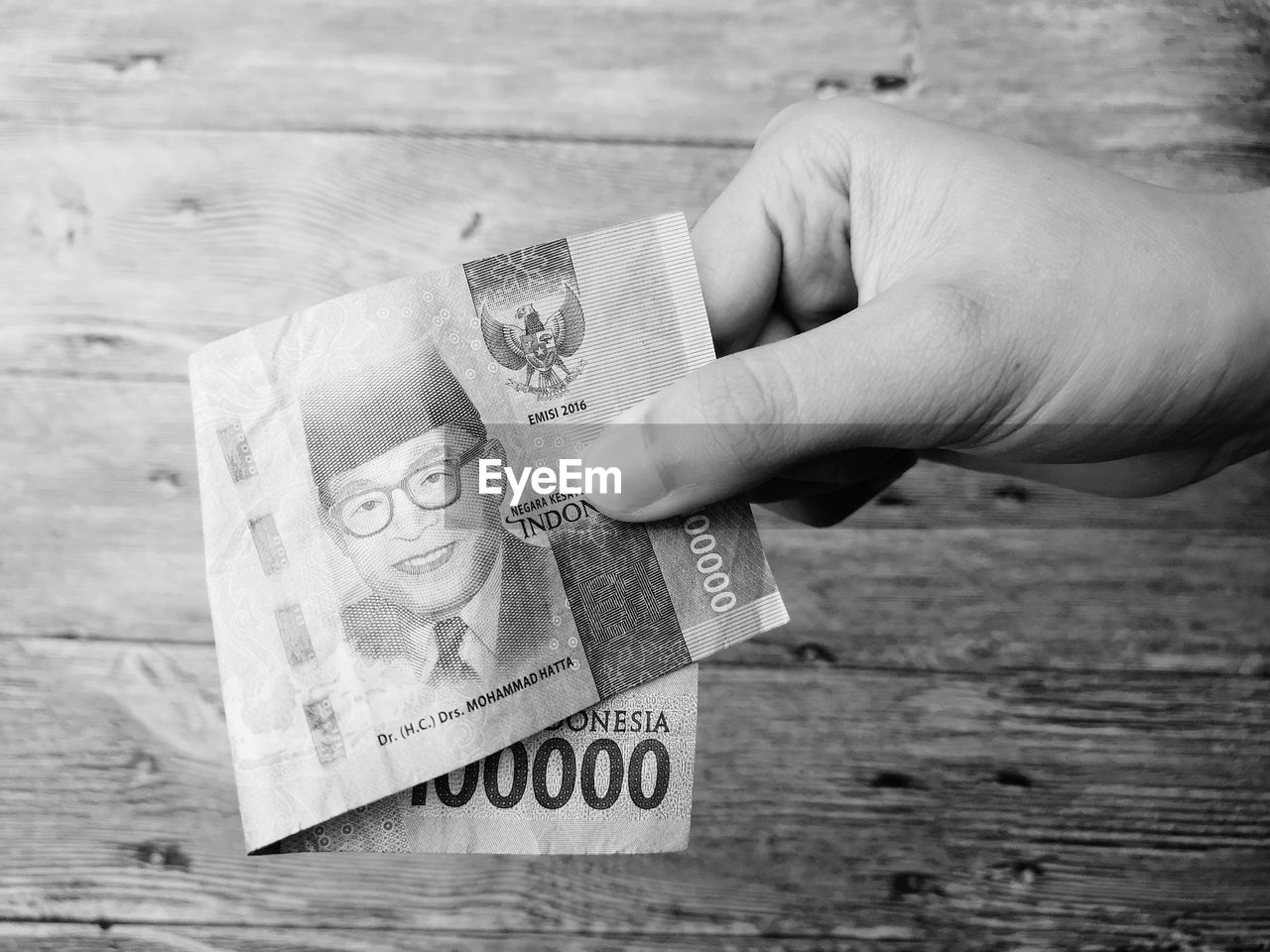 Close-up of cropped hand holding paper currency at table