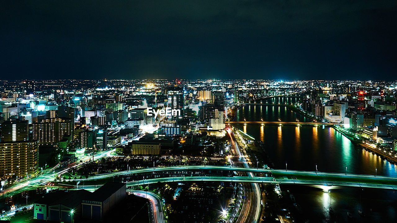 HIGH ANGLE VIEW OF ILLUMINATED BUILDINGS IN CITY AGAINST SKY AT NIGHT