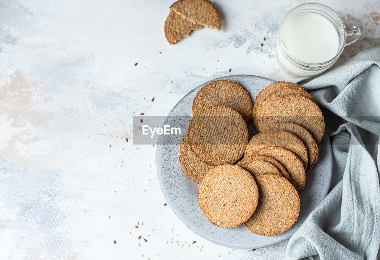 Tasty crackers with seeds on a plate and a cup of milk. snack or breakfast.