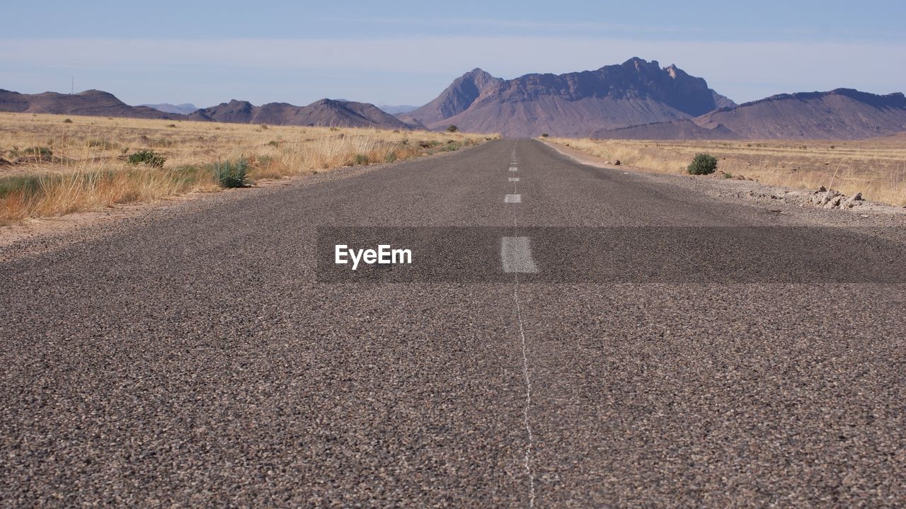 Surface level view of country road against mountain landscape