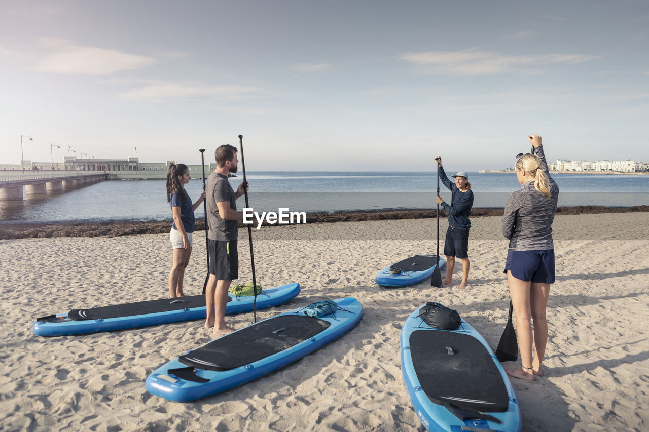 Male instructor training man and women at beach during sunset