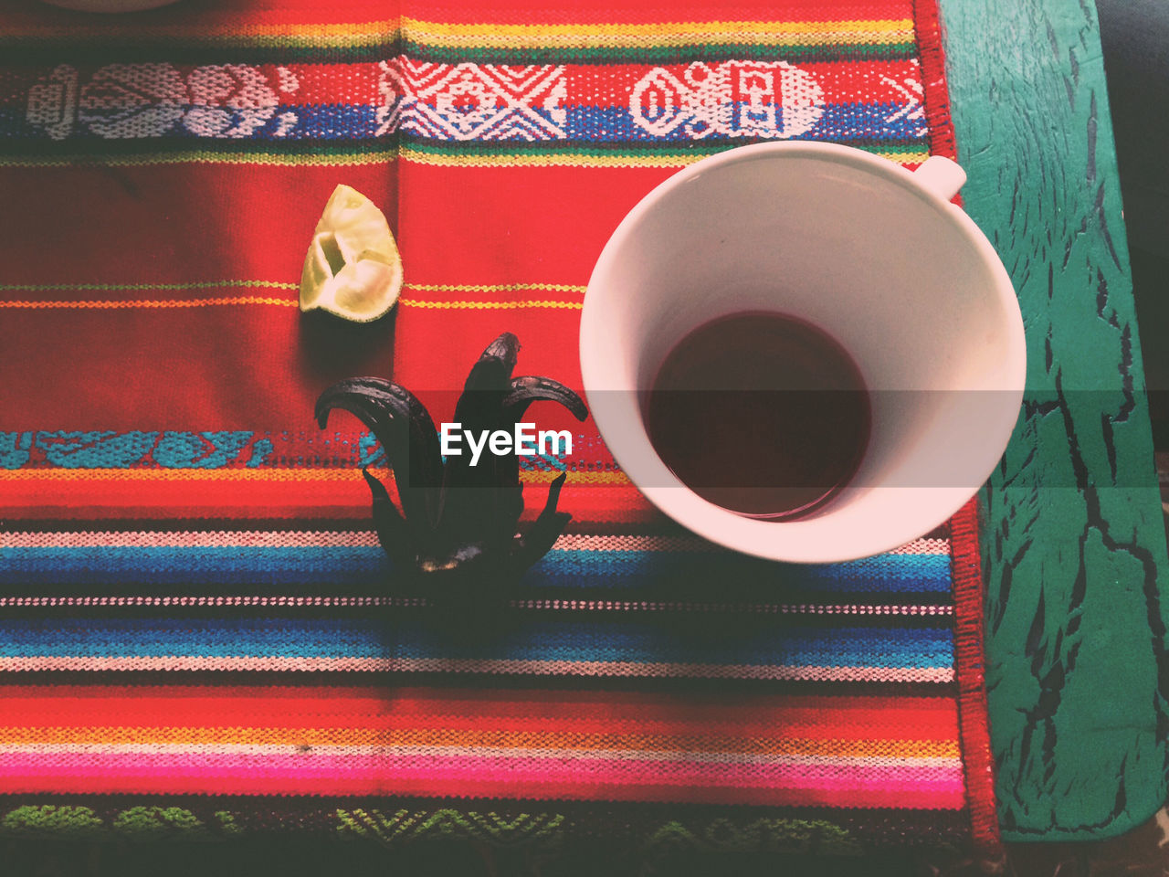 High angle view of coffee cup with food on tablecloth