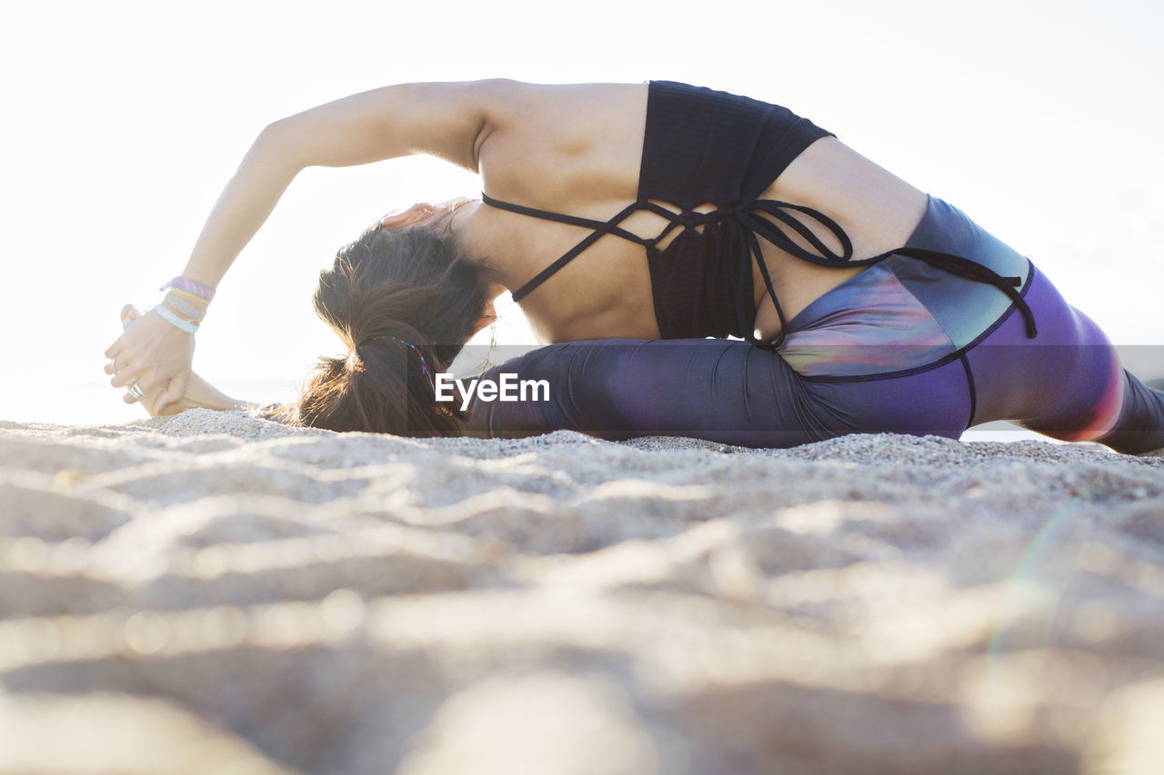 Rear view of woman doing yoga on beach during summer