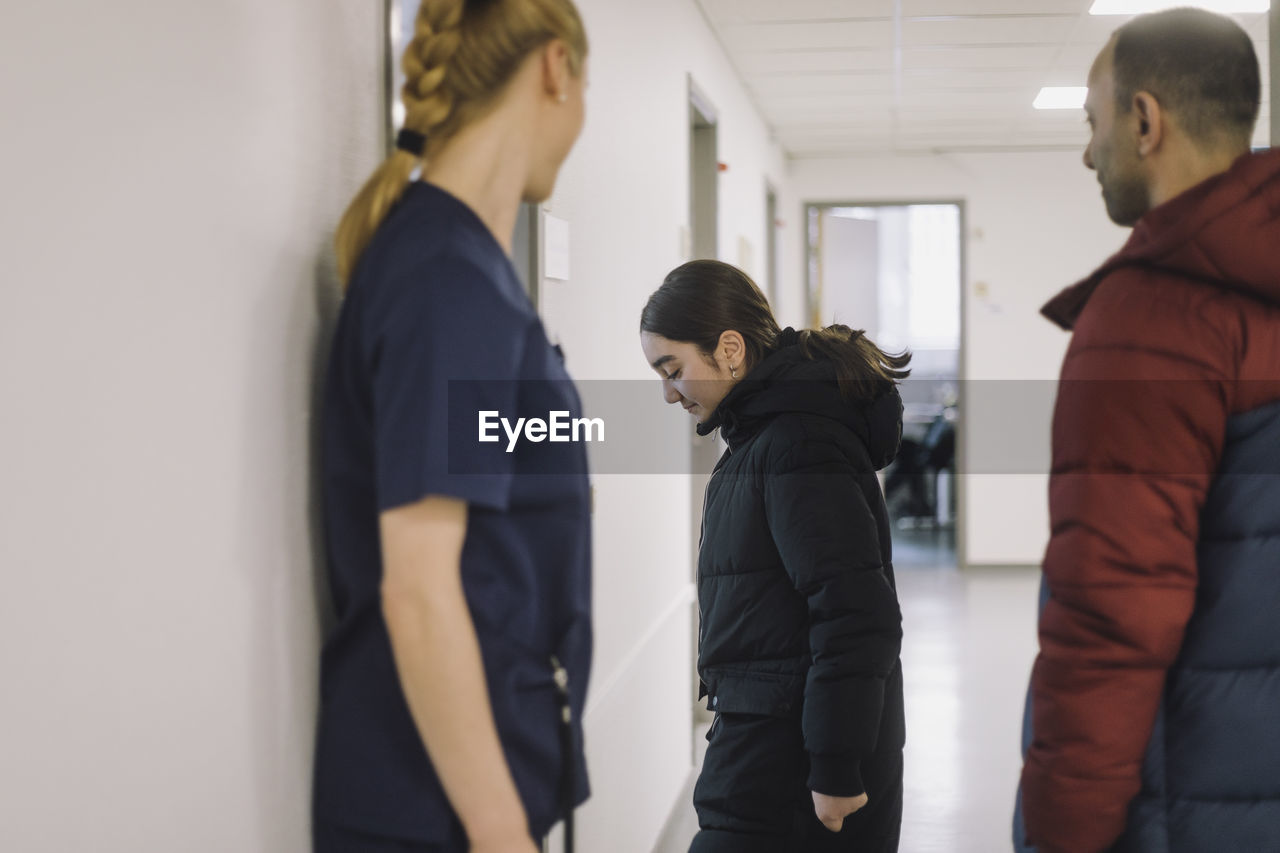 Side view of female patient entering in consulting room with father at hospital